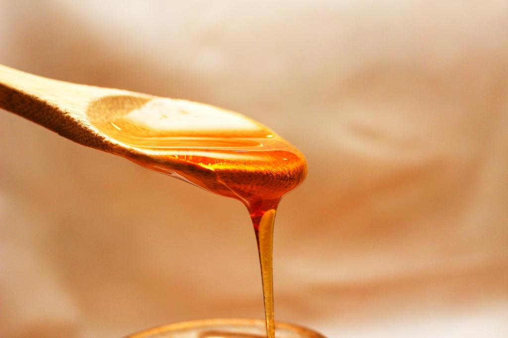 honey flowing from a wooden spoon