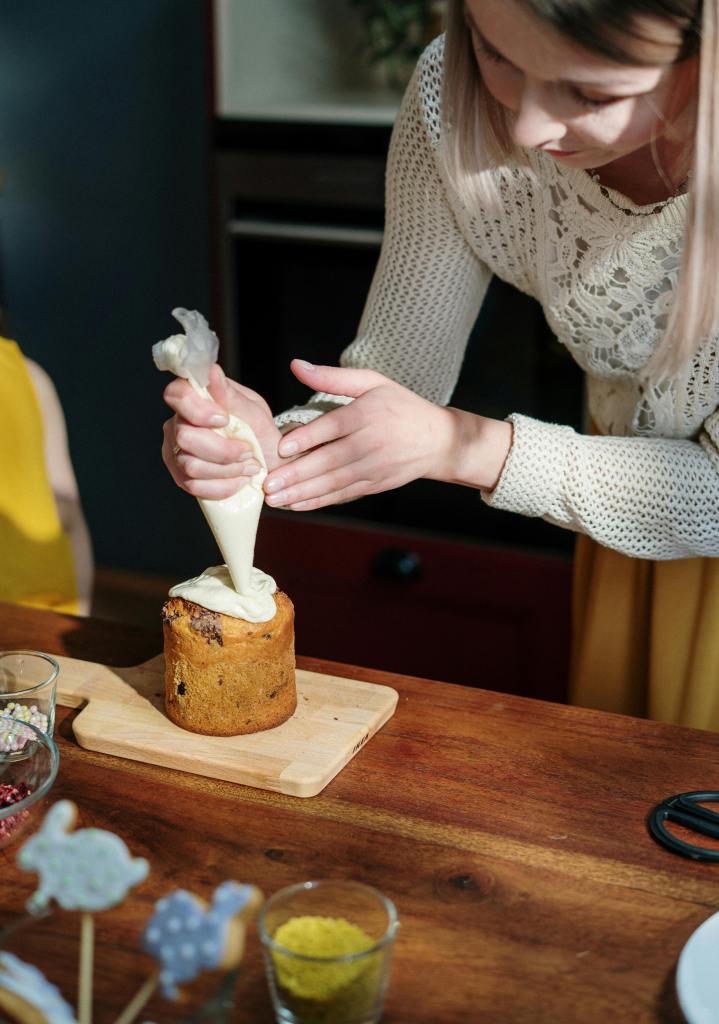 woman covering a cake with white frosting