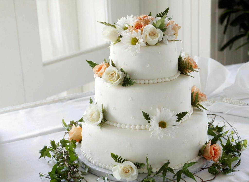 three tier wedding cake decorated with flowers and greenery