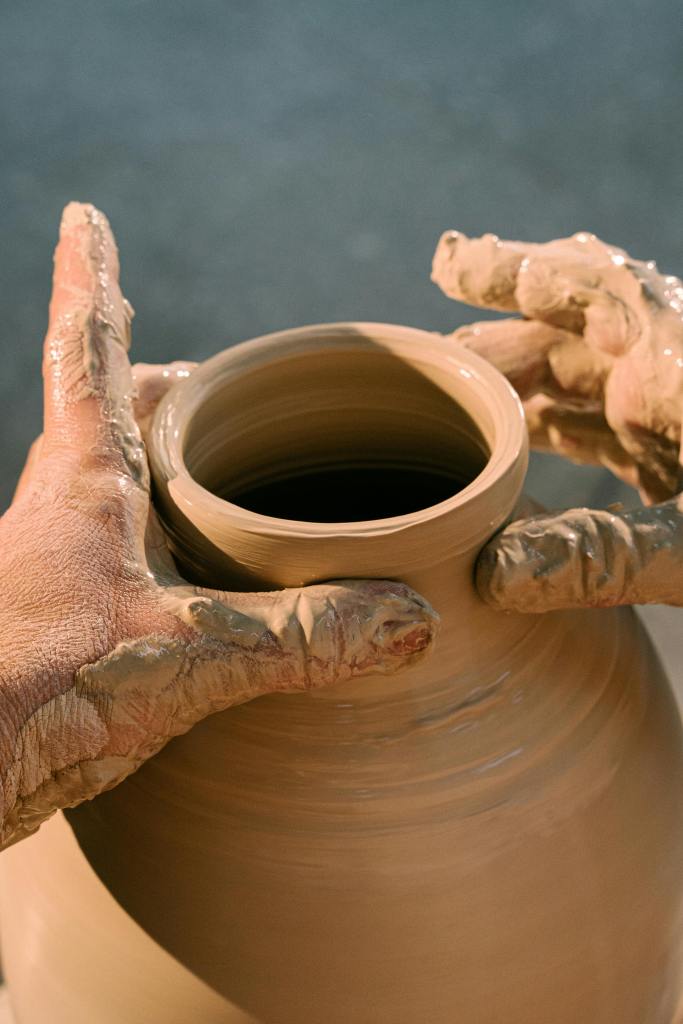 hands shaping a vase on a pottery wheel