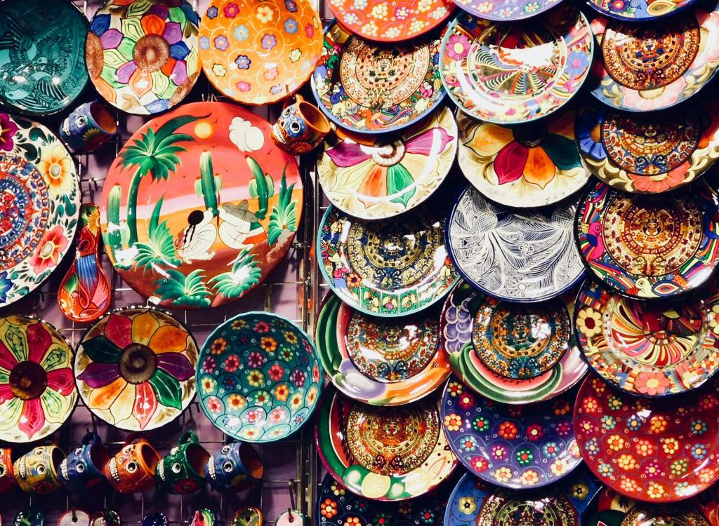a vibrant assortment of densely packed, handcrafted, decorative plates and small cups, likely from an artisan market
