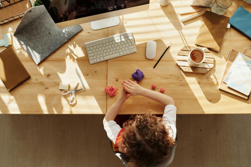 kid playing with colored dough on a wooden table