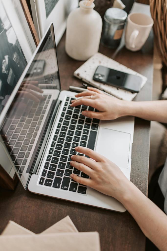 female person using a laptop on a wooden desk