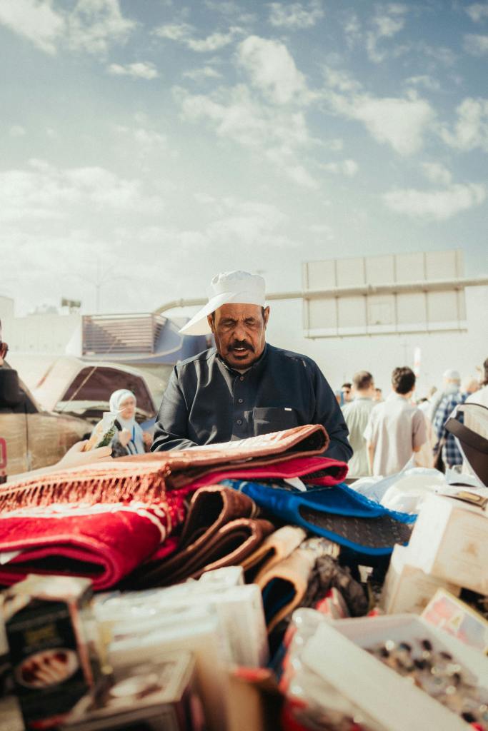 A foreigner merchant in a market with a lot of items in front of him