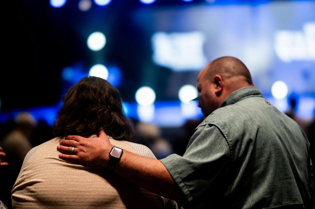 a candid moment of support between two individuals where one person is placing their hand on the other's shoulder for comfort
