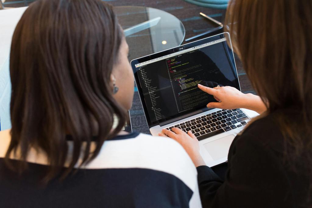 two female developers looking at a code in laptop