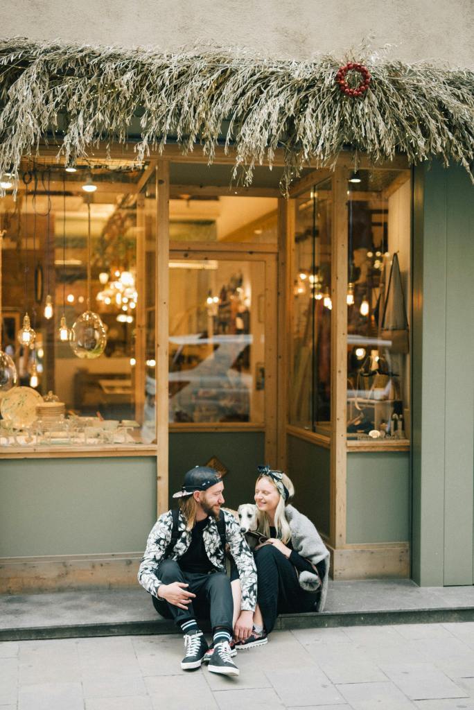 A couple sitting in front of retail shop with their dog in the middle