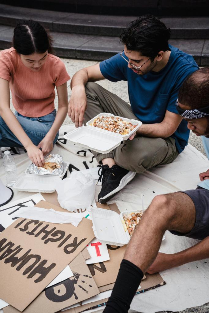 group of people gathering to eat sitting on the floor with sign visible that appears to say rights