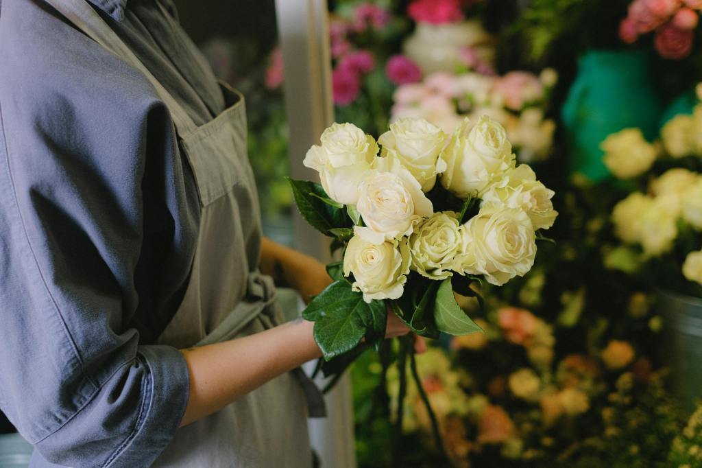 florist holding a bouquet of white roses