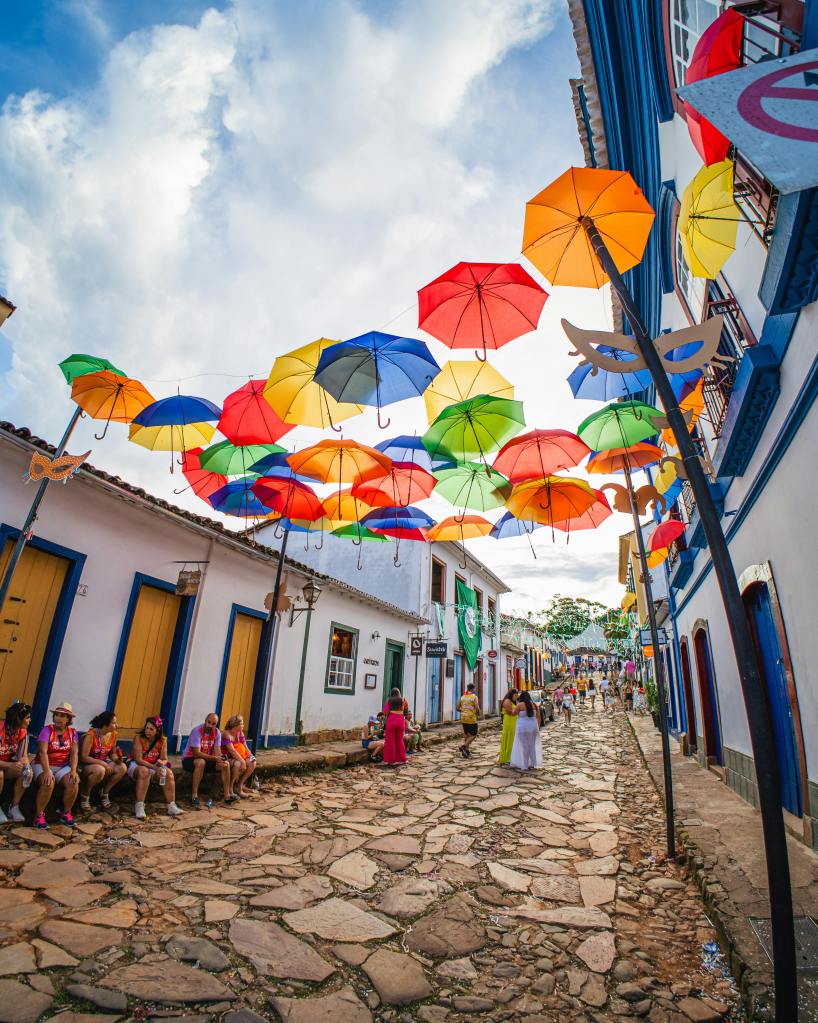 colored umbrellas hanging above a cobblestone a street