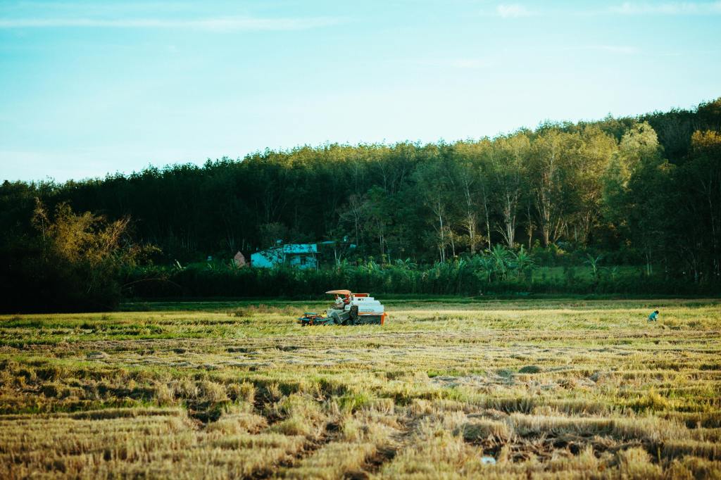 Tractor on green field with a forest in the background