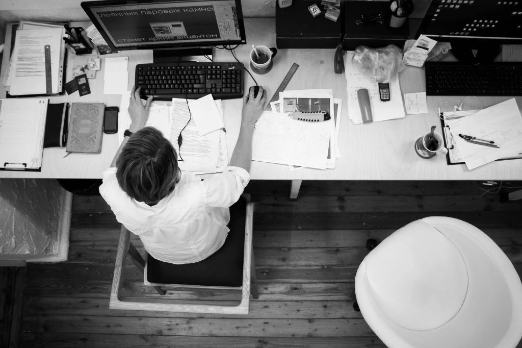 An entrepreneur sitting in front of big table with her phones, screens and notes