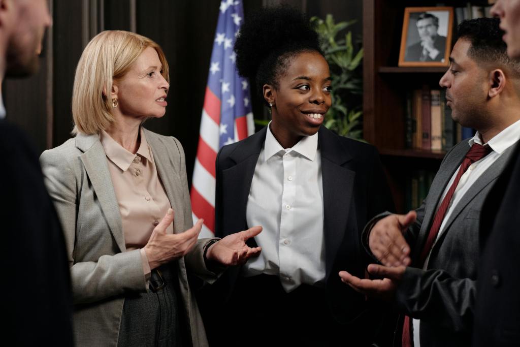 People wearing suits communicating, perhaps politicians or government officials as there is an American flag in the background