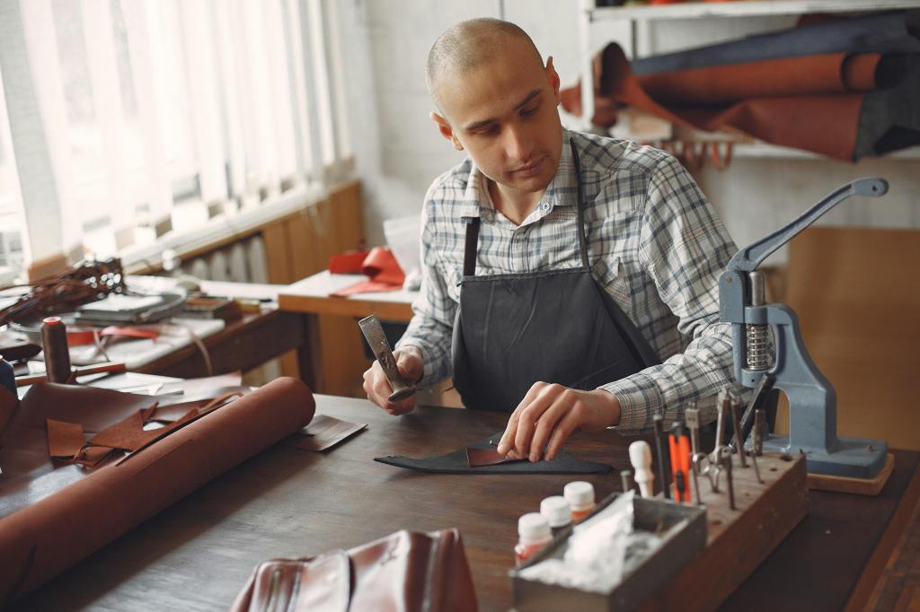Leatherworker holding a hammer working on a piece of leather
