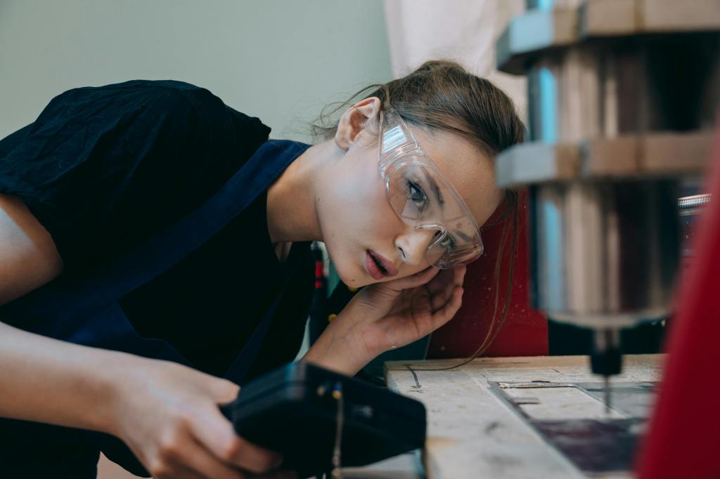 Female worker wearing safety glasses inspecting metal work
