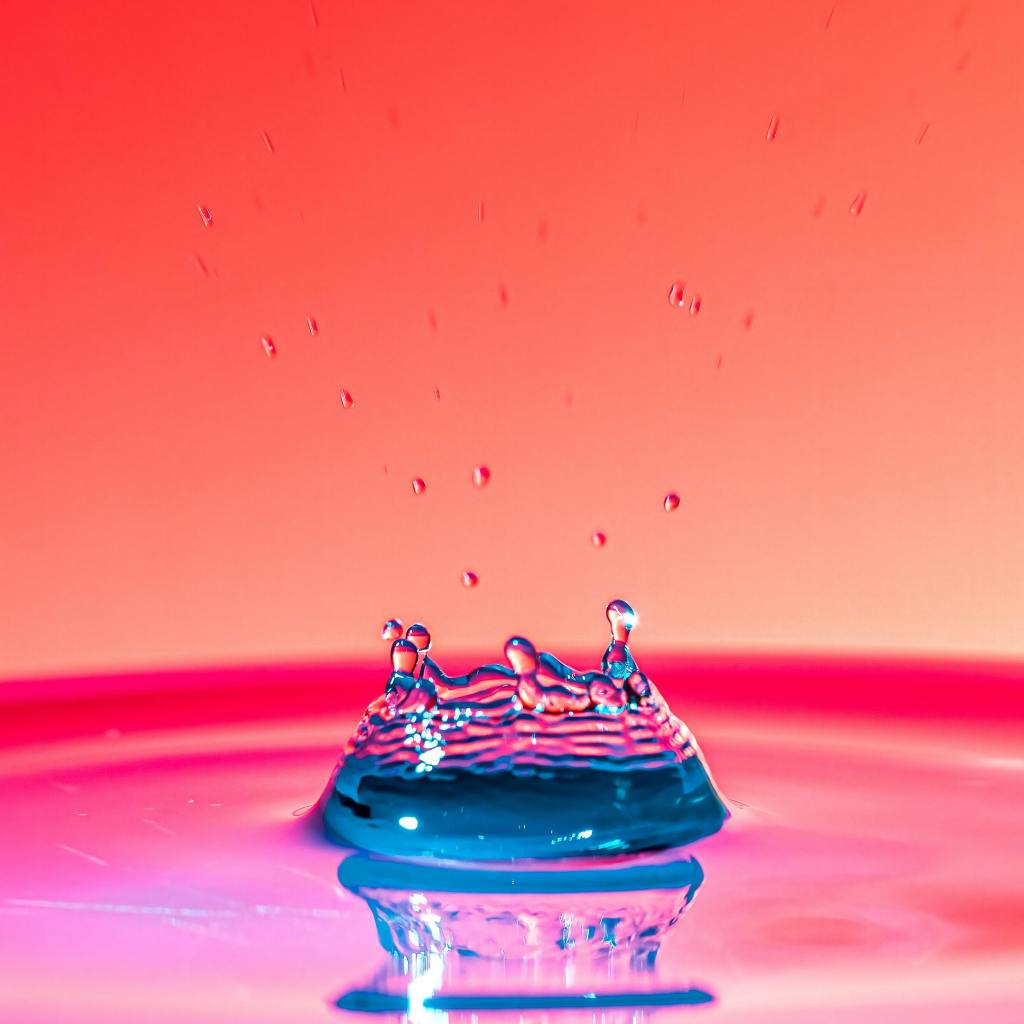 Picture in pinks and oranges of the moment a drop hits water