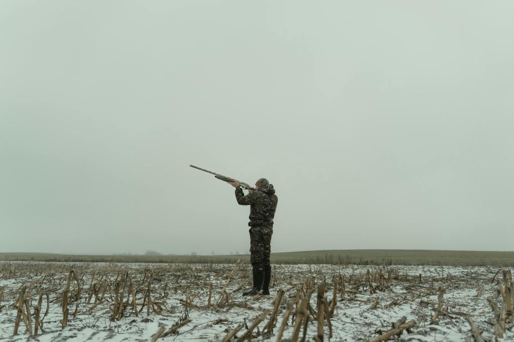 Professional shooter in a field with light snow on the ground