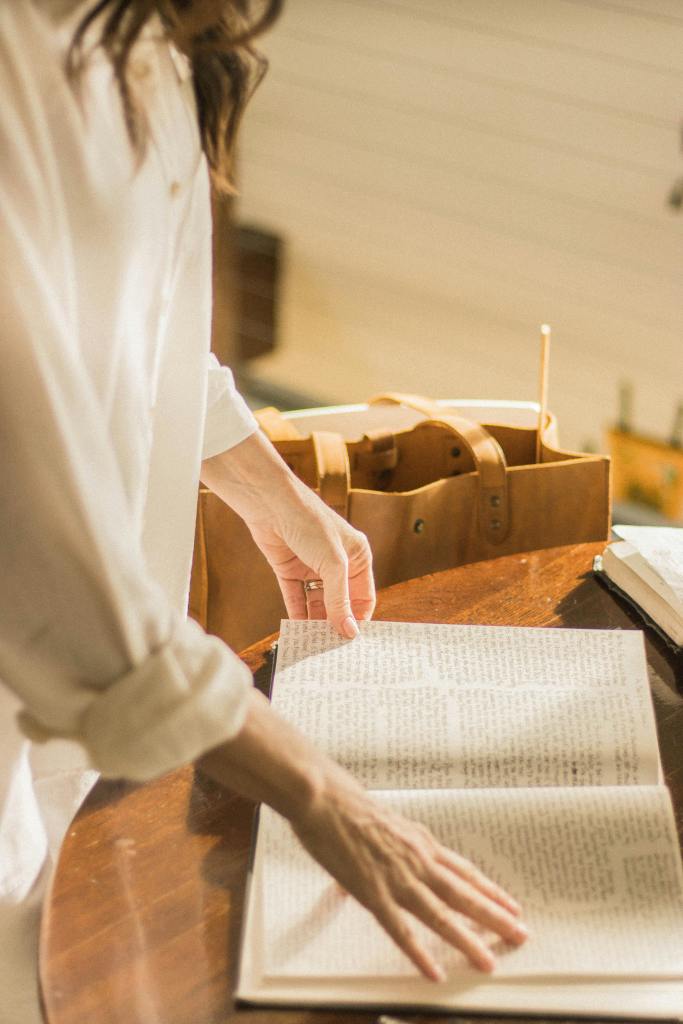 A woman with an open book, the book is on a wooden table