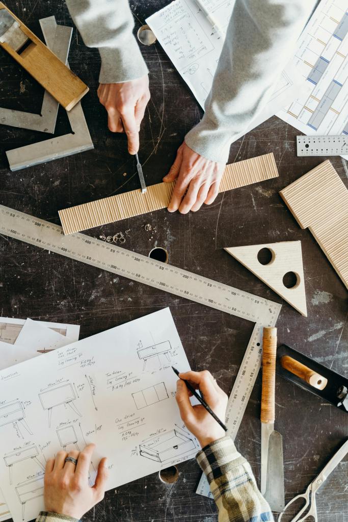 a top-down view of two researchers engaged in a woodworking project at a workbench